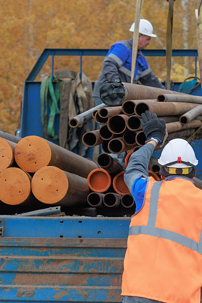 istock Construction Workers Handling Pipes on a Job Site 2239794774