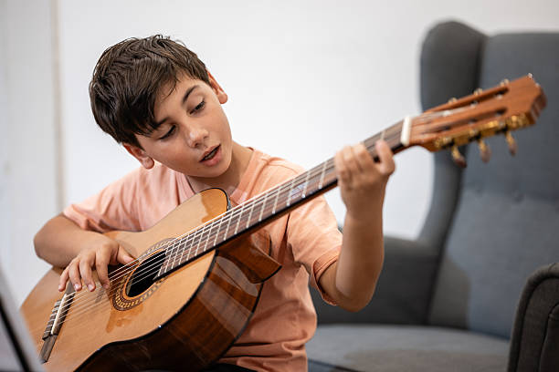 istock Boy learning playing acoustic guitar at home 2239795781