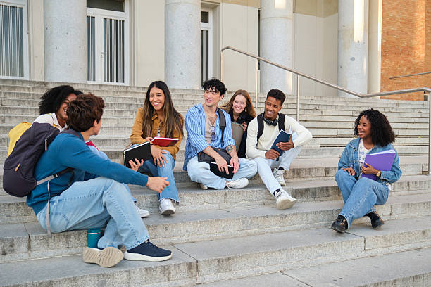 istock Diverse students sitting on campus stairs talking and communicating 2239796555