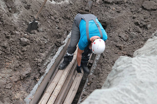 istock Male worker installing pipes in construction trench with safety gear 2239797199