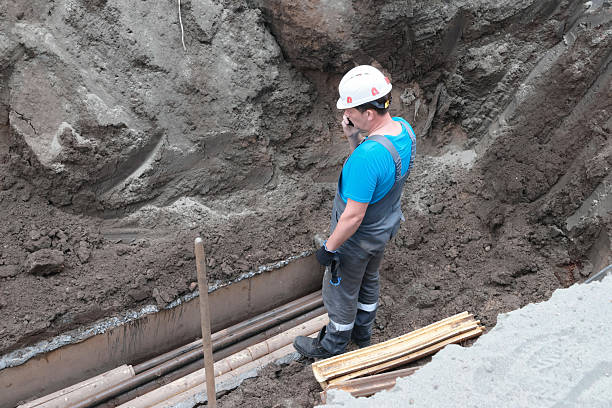istock Male construction worker inspecting pipes in excavation site 2239797415