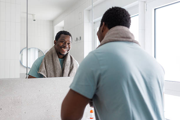 istock Smiling young African American man looking in the mirror 2239797429
