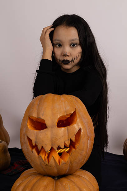 istock Little girl sitting on table with pumpkin, smiling brightly 2239810170