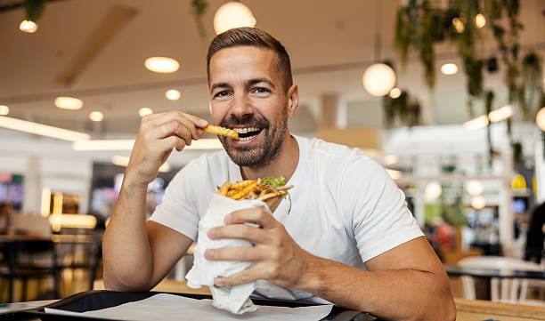 Smiling bearded man enjoys gyro and fries at a casual restaurant, relaxed lunchtime street-food moment of comfort and satisfaction