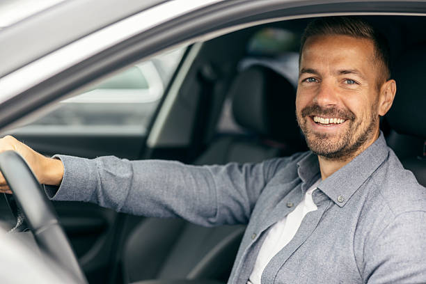 istock Happy man driving car looking at camera 2239811568
