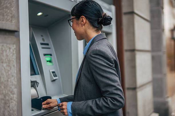 istock Woman using atm for banking transaction and withdrawing cash 2239811906