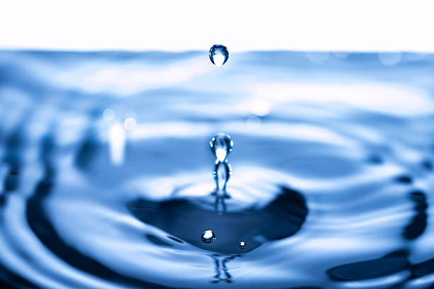 Water drop splashing on the surface of the water in a blue background.