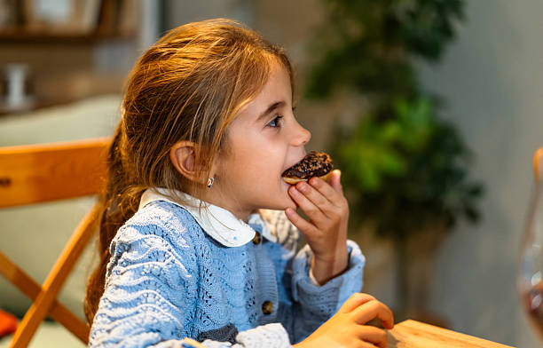 istock Girl eating a donut at home 2239812752