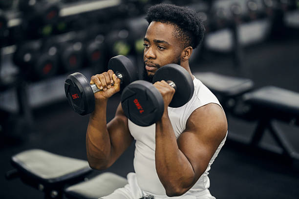 istock Young black man exercising with dumbbells in gym 2239818128