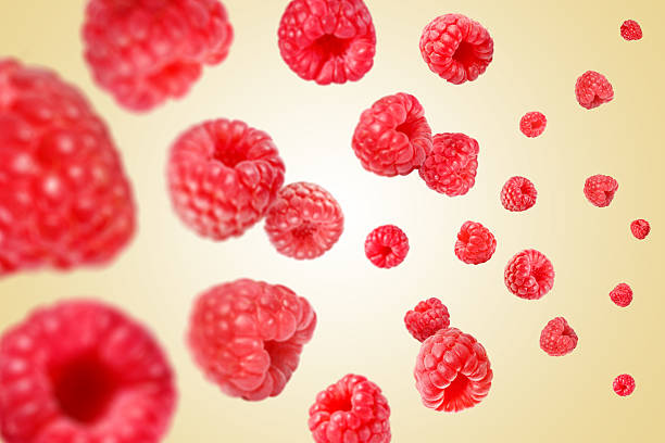 istock Fresh raspberries swirling in air against beige background 2239818193