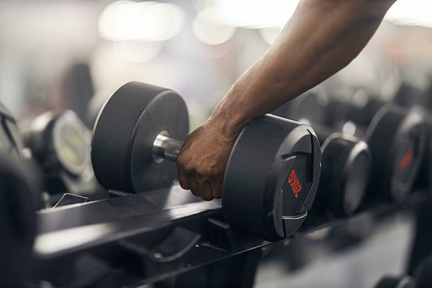 istock Man's hand picking up dumbbell from rack 2239818226