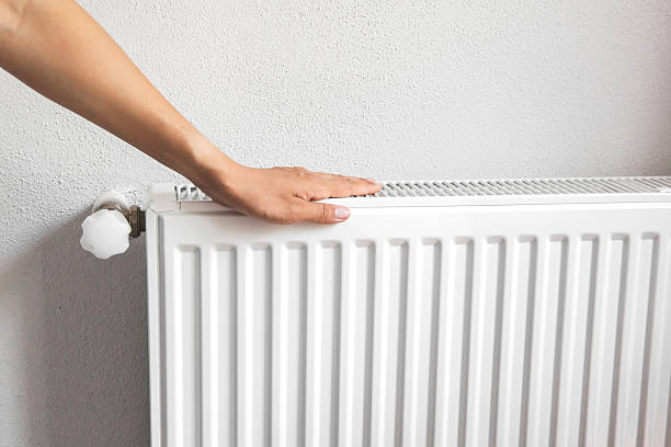 istock Human hand touching white metal radiator against light wall, checking warmth during heating season, symbolizing home comfort, energy efficiency and indoor climate control concept 2239818938