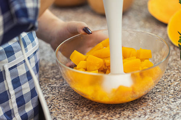 Woman using blender for preparing pupkin potage