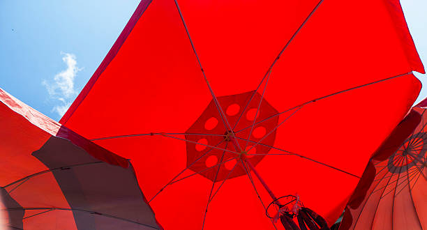 istock Vivid red beach umbrellas creating an abstract geometric pattern against a clear blue sky with soft white clouds, symbolizing summer holidays, warmth, sunny leisure, and outdoor relaxation 2239825580