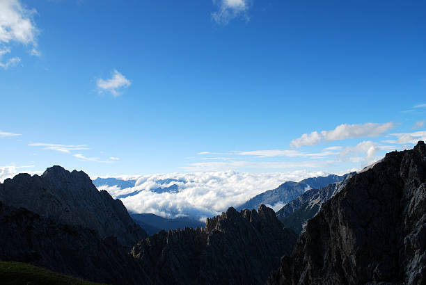 Expansive mountain horizon with deep valleys and layered ridges, photographed in warm evening light. The Bavarian Alps glow under the setting sun, highlighting natural beauty and wilderness.