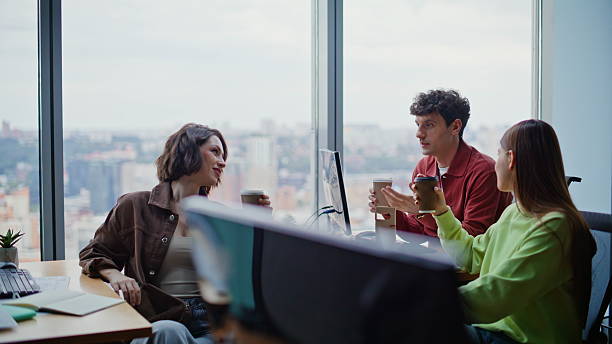 istock Relaxed startupers holding coffee cups talking office closeup. Three coworkers 2239827487