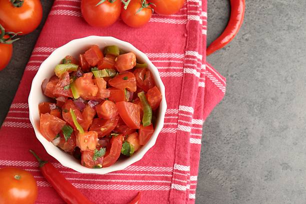 istock Delicious salsa (Pico de gallo) in bowl and ingredients on grey textured table, flat lay. Space for text 2239829752