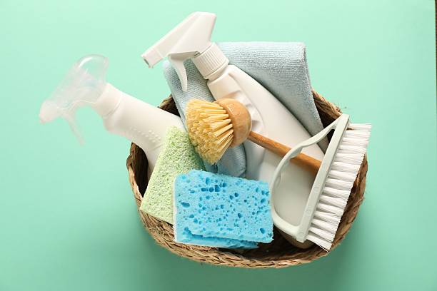 istock Different cleaning products and tools in wicker basket on turquoise background, top view 2239830561