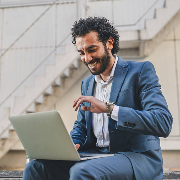 istock Smiling businessman working on laptop outdoors in urban setting 2239831026