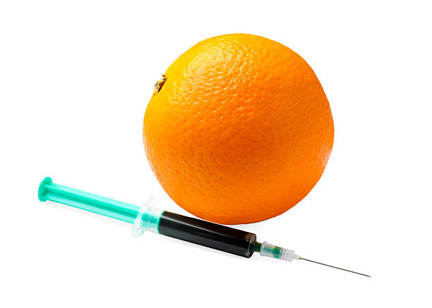 istock GMO concept. Fresh orange and syringe isolated on white 2239831094