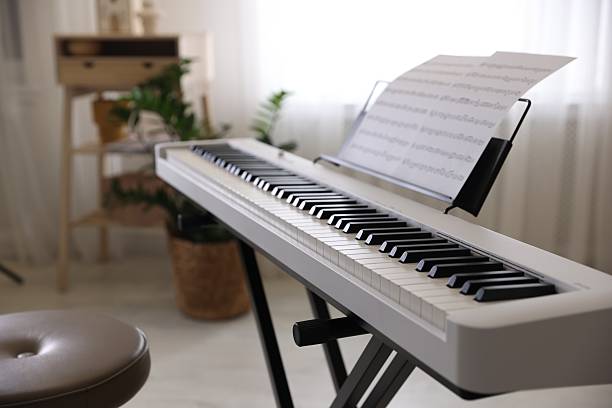 istock Synthesizer with music sheets and stool indoors, closeup 2239831307