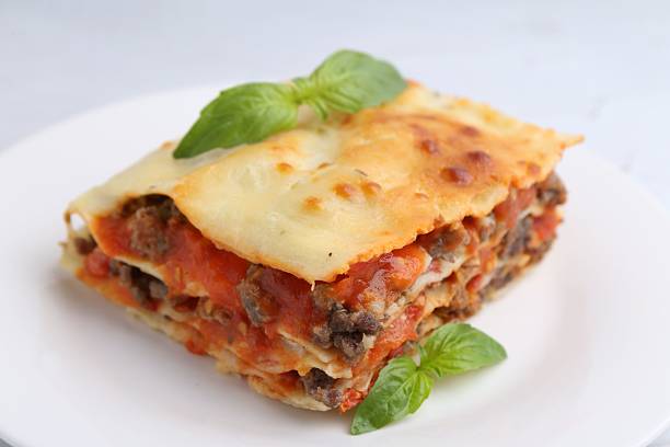 istock Piece of delicious cooked lasagna with basil on plate, closeup 2239832706