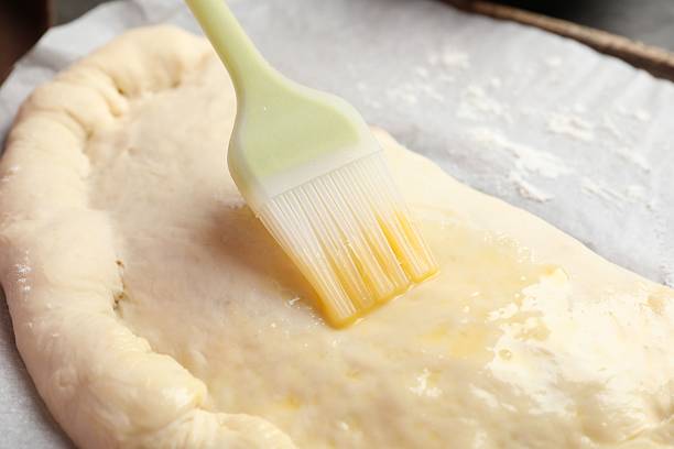 istock Brushing egg yolk on calzone pizza at table, closeup 2239833374