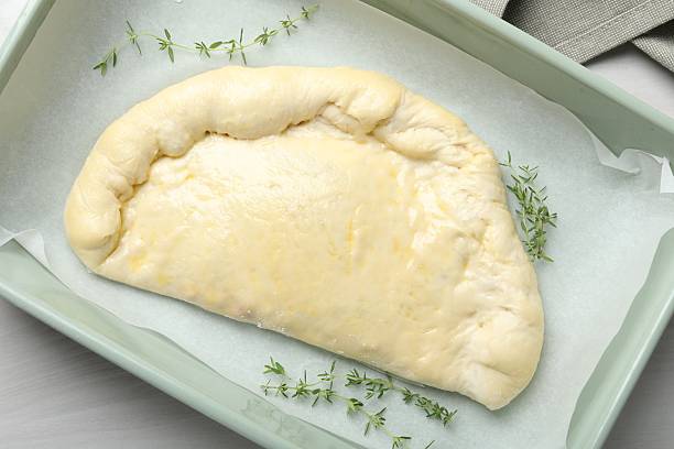 istock Uncooked calzone pizza in baking dish on white wooden table, top view 2239833471