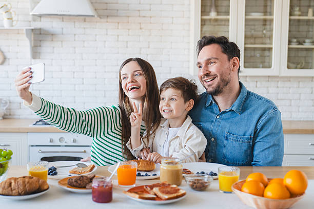 istock Caucasian family making selfie shot while have healthy breakfast in light modern kitchen interior, parents with little son boy enjoying tasty food and drinking orange juice while sitting at table 2239833517