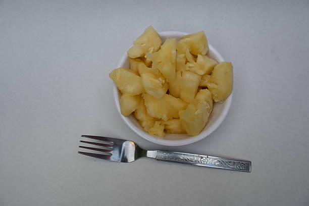 Pineapple or Ananas comosus slices on white background. It is a tropical plant with an edible fruit. It is plant in the family Bromeliaceae. Pineapple pieces in a bowl ready to eat.