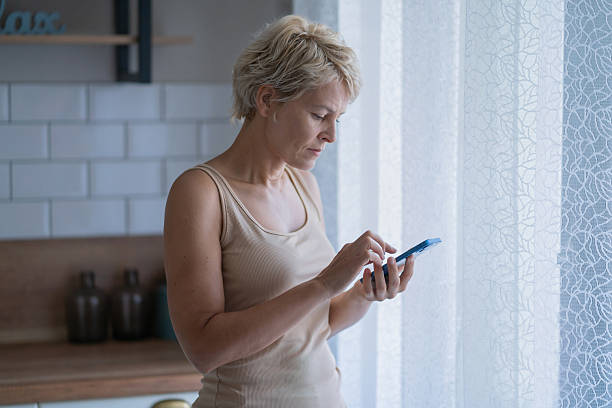 istock Thoughtful Woman Using Smartphone in Bright Room 2239842991