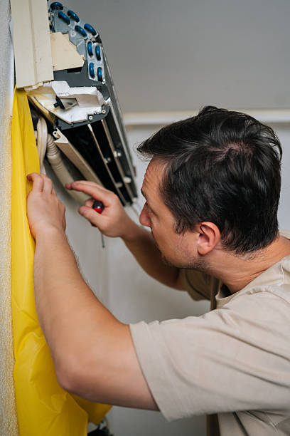 istock Close-up of skilled HVAC professional disassembling wall-mounted air conditioning unit, using yellow drainage bag while carefully accessing electrical components 2239843414