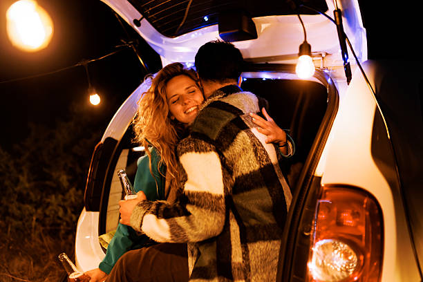 istock Couple enjoying a cozy evening with drinks in the car while surrounded by warm lights at a peaceful outdoor location 2239843662