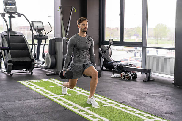 istock Athlete Performing Lunges with Dumbbells in the Gym 2239844040