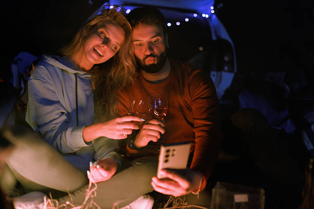 istock Couple enjoying a cozy campfire gathering while using a tablet in a scenic outdoor location at night 2239847944