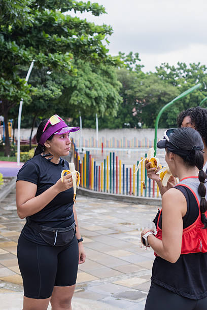 Women runners eating bananas in park after training