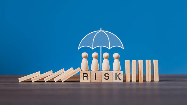 istock A business team at the workplace is protected under an umbrella while falling dominoes are stopped, illustrating risk management, insurance protection, and safety strategy in organizations 2239855178