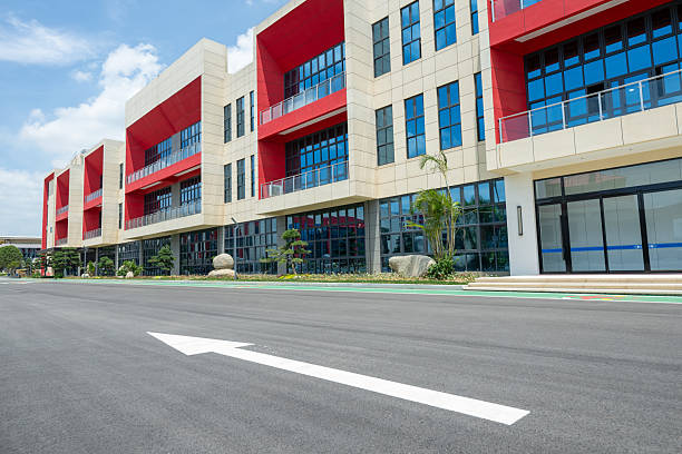 A modern red building within a factory, set against a blue sky. The main scene features an architectural structure with large windows and a central walkway. The visual style is modern and minimalist, conveying a sense of openness and innovation. Potential uses include educational institutions, corporate offices, or real estate promotions.