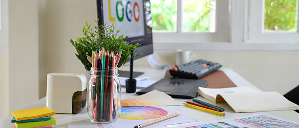 istock creative designer workspace with colored pencils in a jar, color palettes, and computer screen displaying a logo design 2239858088
