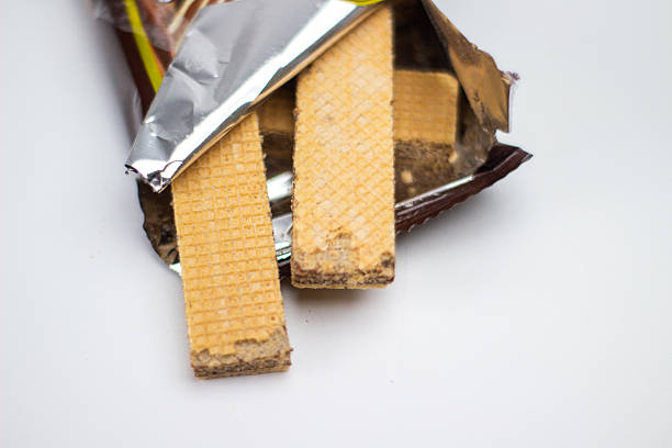 istock Two wafer sticks with chocolate cream peek from foil wrapper in a simple studio shot. 2239860739