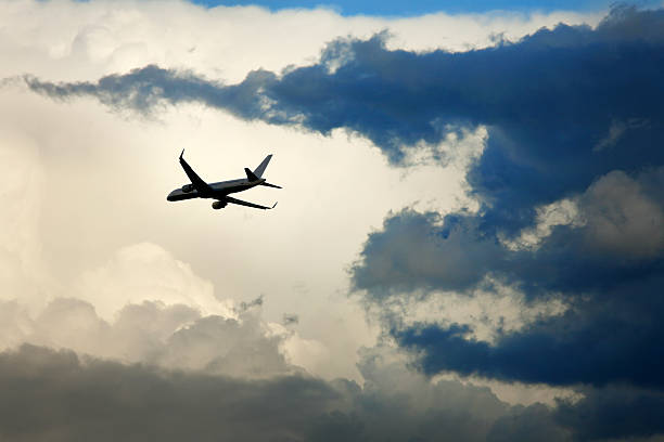Close up flying commercial airplane over dramatic sunset sky