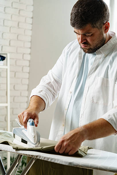 istock Man ironing clothes at home while preparing for a productive day ahead in a bright room 2239870702