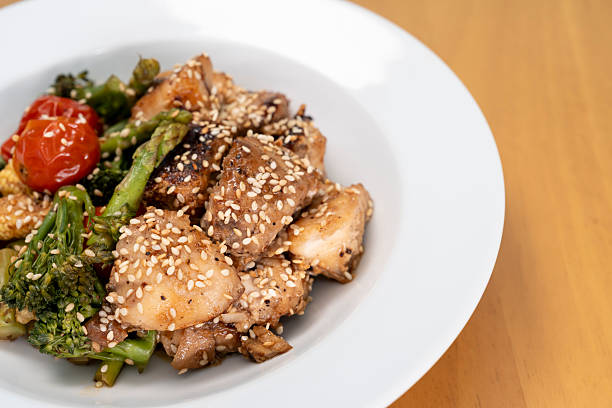 istock Stir-fried red snapper with teriyaki sauce and various vegetables: broccoli, tomatoes, asparagus, and baby corn on wooden table. 2239875282