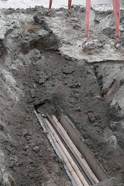 istock Deep excavation revealing underground pipes for urban construction site 2239875806