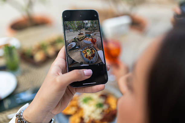 istock Person Holding Smartphone While Capturing Outdoor Dinner Table Scene With Pasta Feast 2239877888