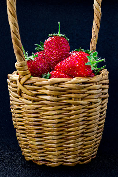 Fresh ripe strawberries in a white bowl on a white wooden background