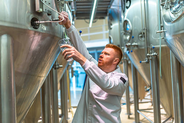 istock Brewmaster sampling beer from stainless steel tank in craft brewery 2239878971