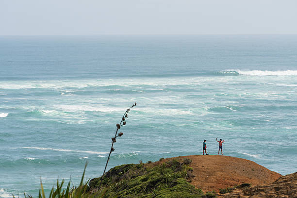 Boys stand playfully on a hill, overlooking the vast expanse of the sea, capturing a moment of joy against a stunning ocean backdrop.