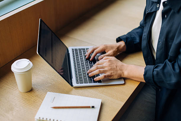 istock Person using a laptop at a desk with a coffee cup and notebook 2239880417