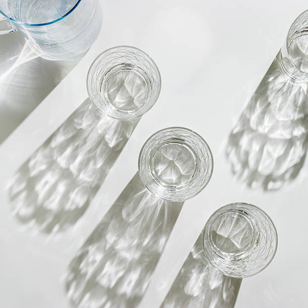istock Water Glasses and water jug with Shadows and sunlight Reflection on white background, colored photo minimal style, aesthetic summer still life, refraction throug crystal shine cups, caustics 2239881924